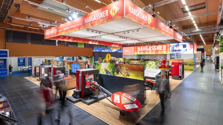 Webuild Hargassner Messestand mit Personen im Gang